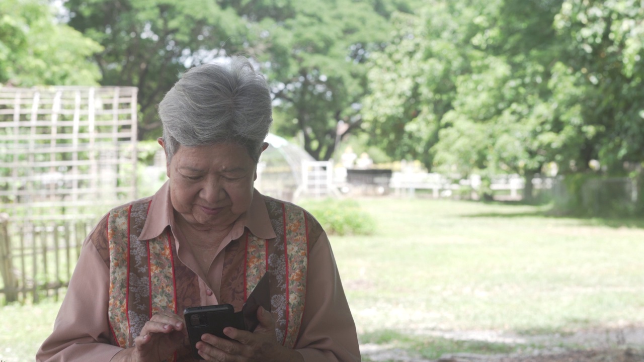 亚洲老人、老人、老年妇女、老人在户外使用手机、智能手机。成熟的退休生活视频素材