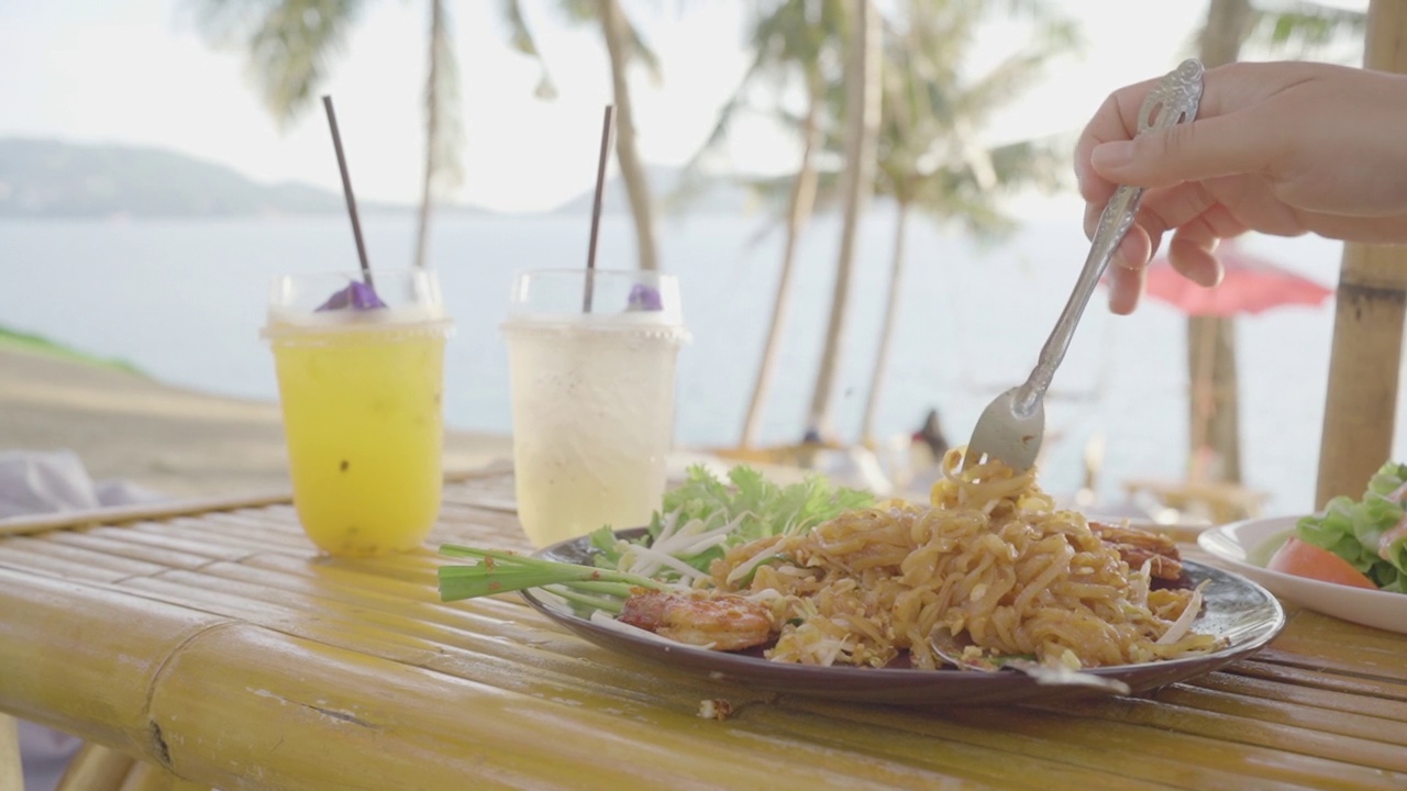 特写泰式炒河虾盘椰子树岛海滨背景。泰国著名的食物。视频下载