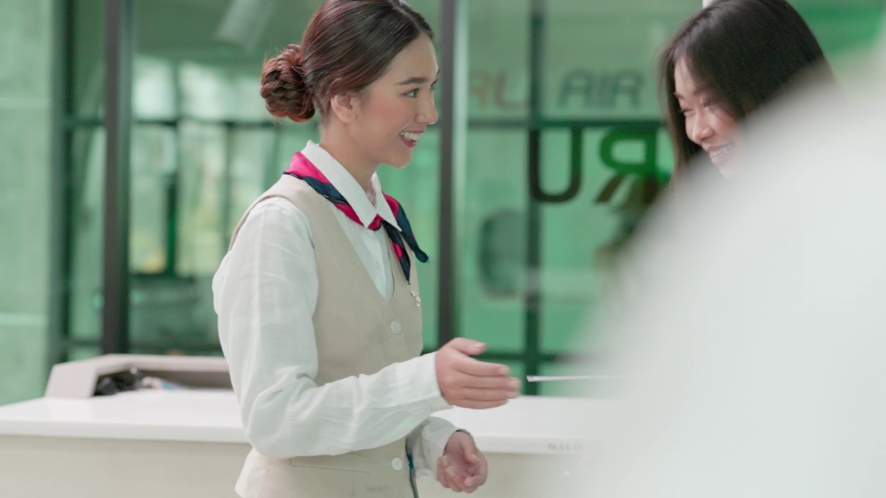 一名乘客将他的护照和登机牌交给空乘人员。在机场的值机柜台，一位亚洲女性视频素材