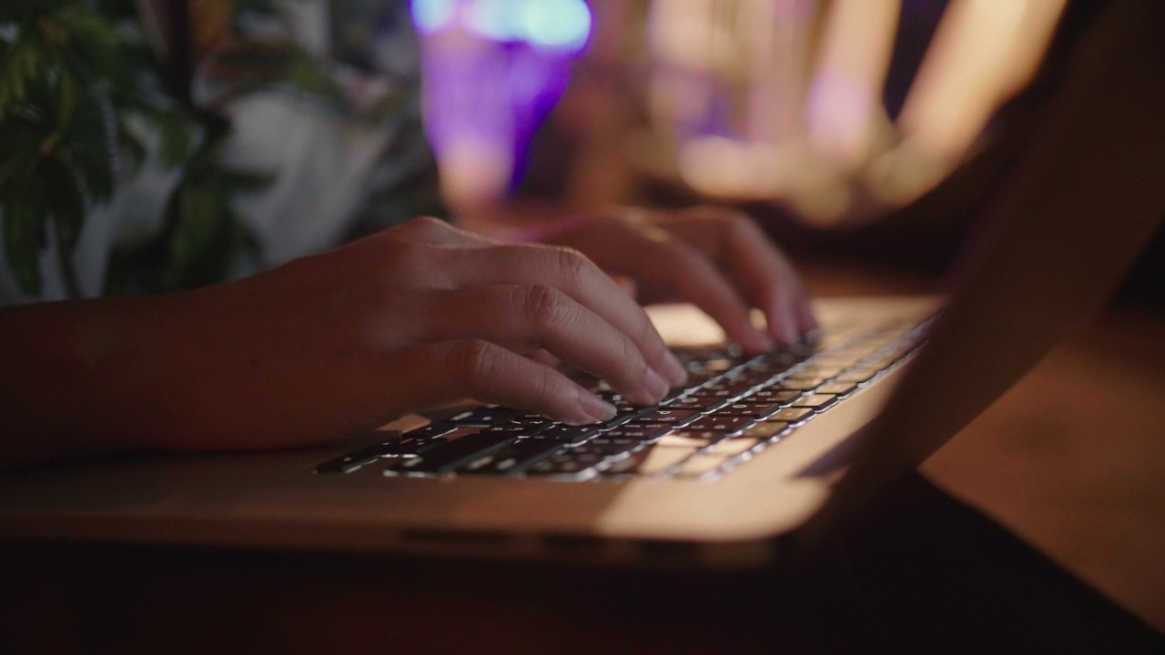 近距离的女人的手在键盘上打字，使用笔记本触摸板在度假享受在海边的晚上。视频素材