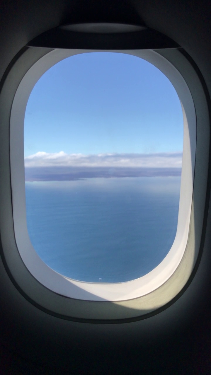 从机场起飞后，从飞机经济舱的窗口俯瞰晴朗天空下加拉帕戈斯群岛的风景。视频素材