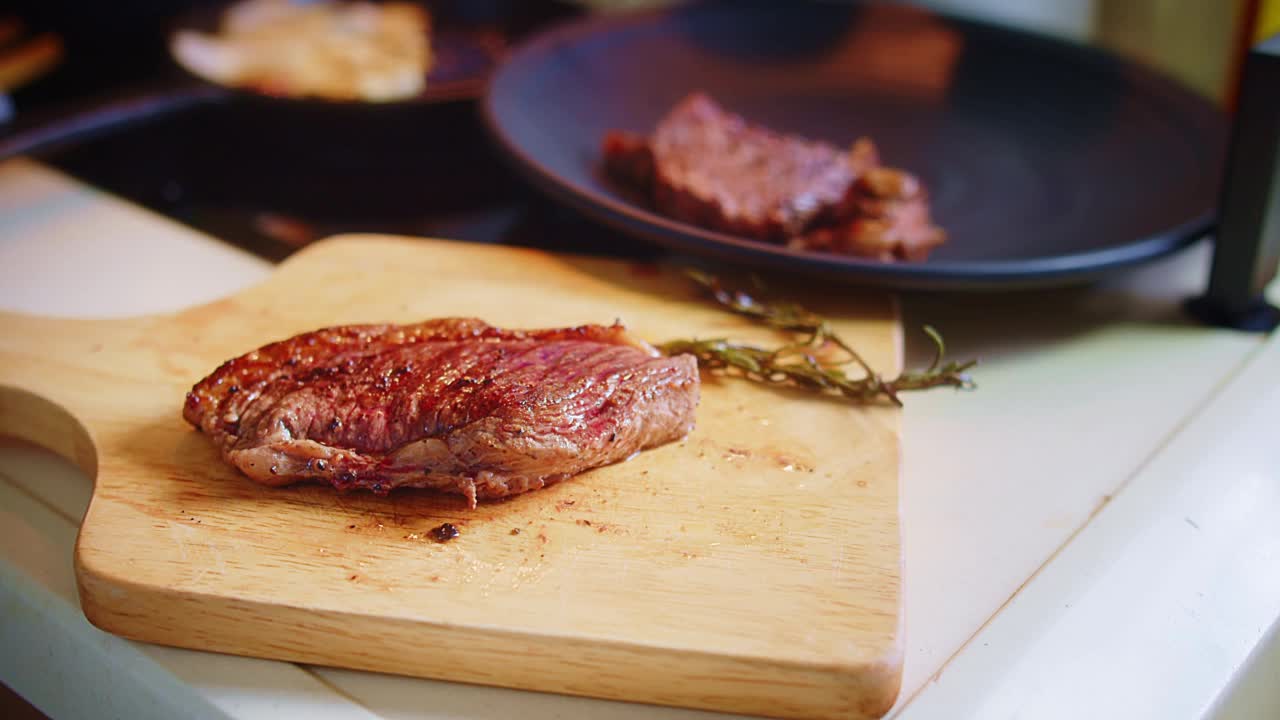 近距离厨师切切片烤多汁新鲜烤肉牛排与叉子和刀在木制砧板在厨房视频素材