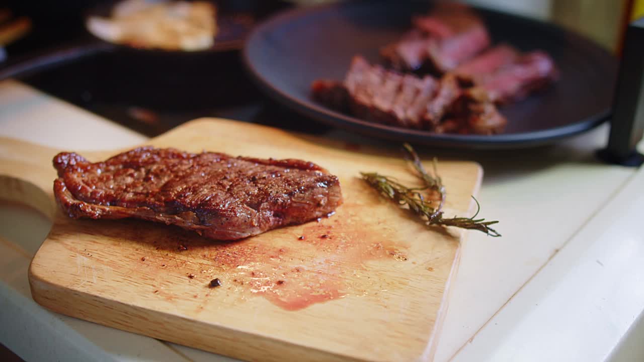 近距离厨师切切片烤多汁新鲜烤肉牛排与叉子和刀在木制砧板在厨房视频素材