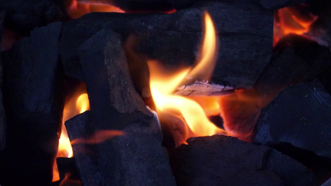 慢动作速度特写场景上燃烧的木炭堆与灰烬和火花散落吹起，海市蜃楼的幻觉运动从热气流，亮橙色的颜色的活煤视频素材