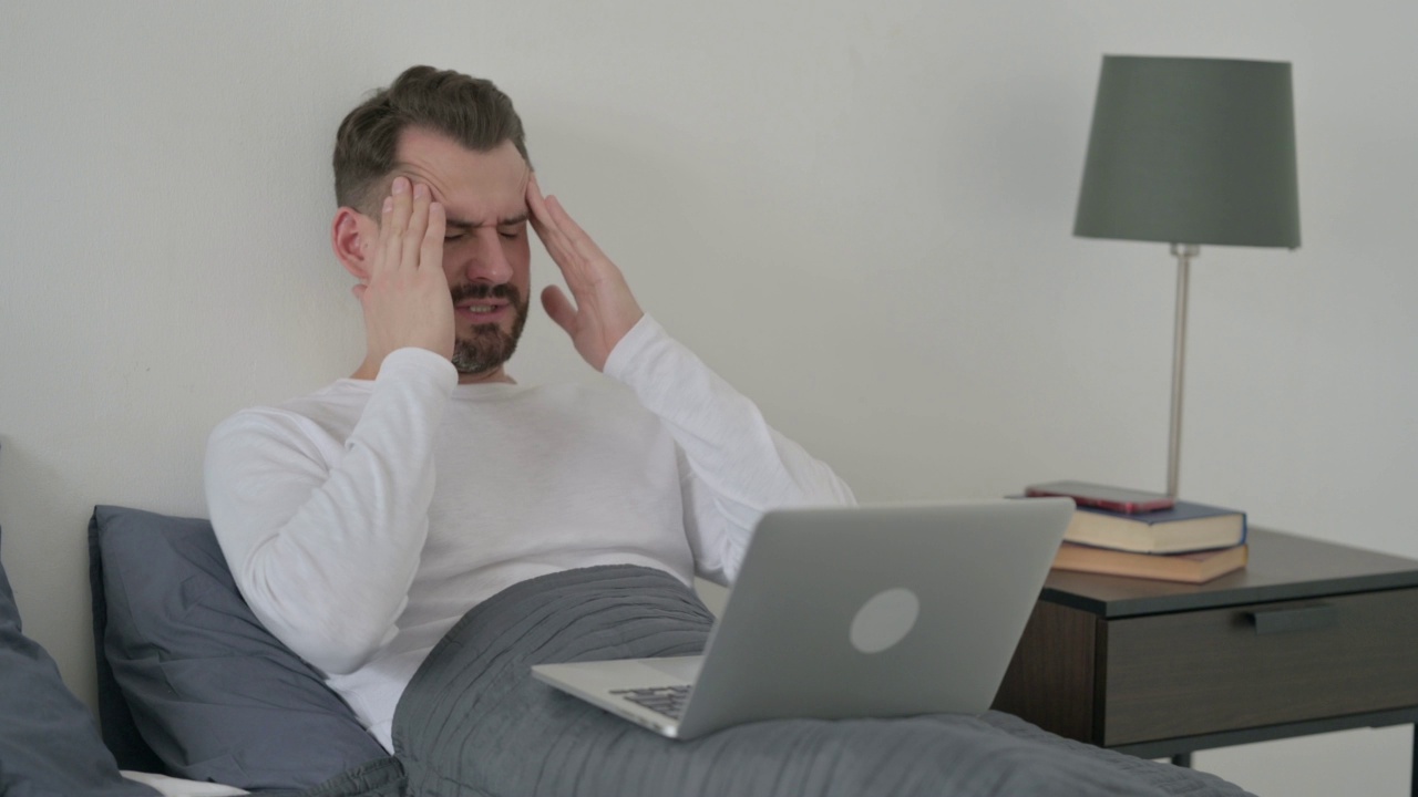 使用笔记本电脑的人在床上头痛视频素材