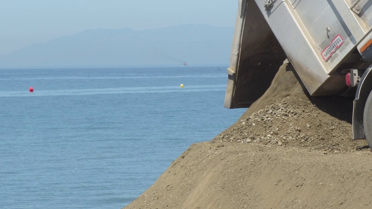 在海滩上一起卸沙的卡车。海滩代作品视频素材
