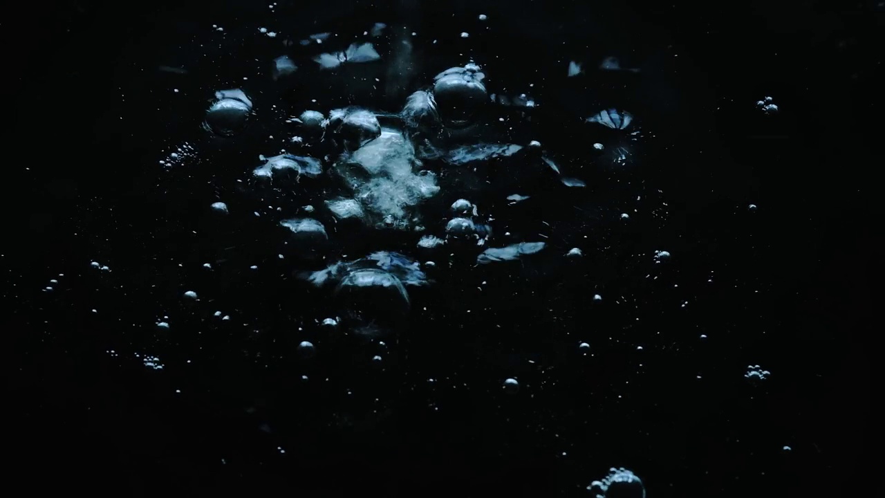 在黑色背景上画出水中的气泡。水滴滴落在水面上视频素材
