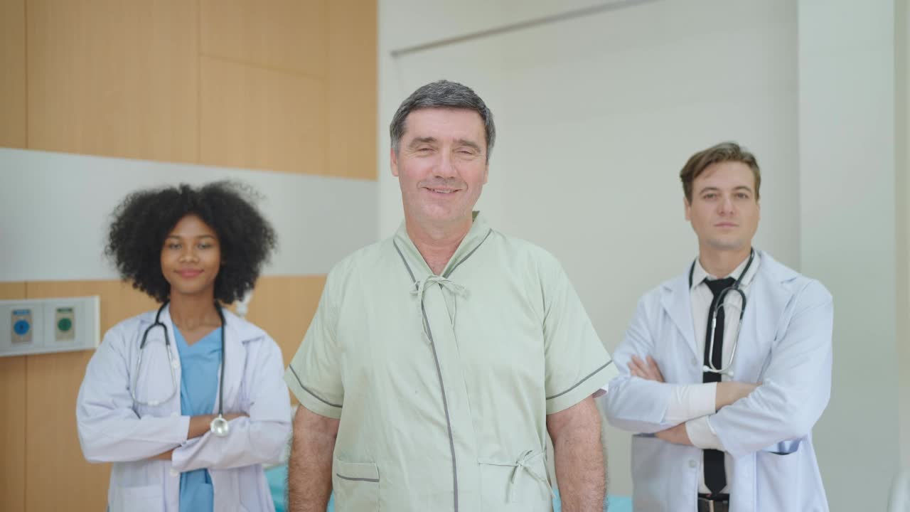 微笑着接受治疗的病人看着镜头，医疗多元化团队站在病房后面。老年人保健理念。视频素材