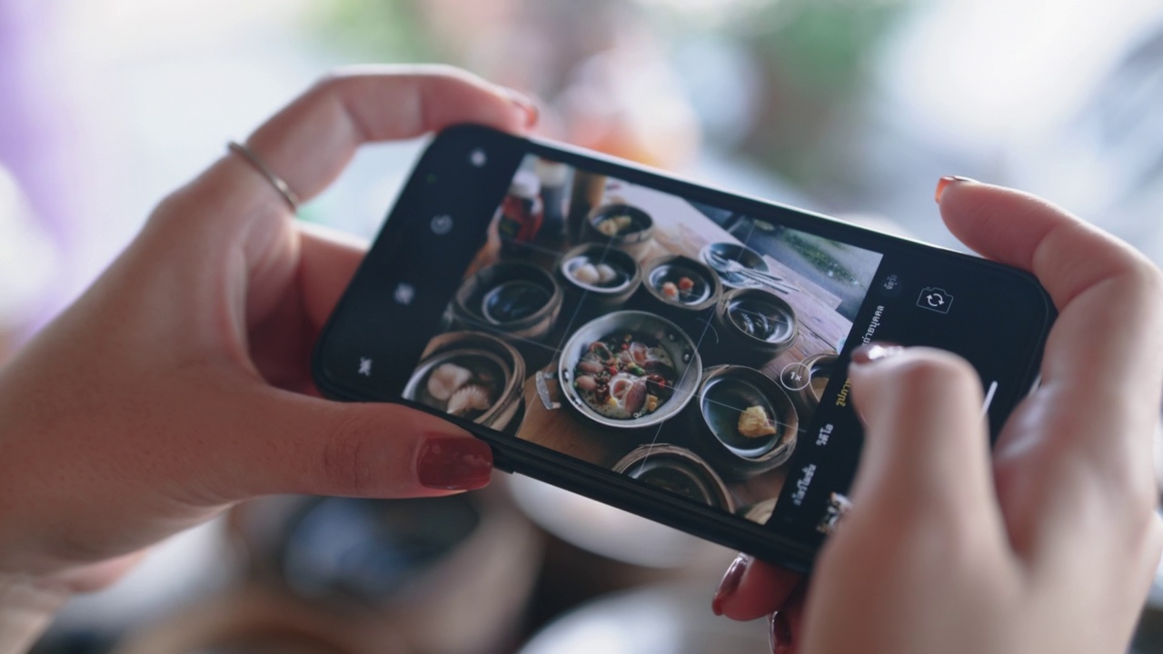 亚洲女人用手机拍桌子上的食物。视频下载