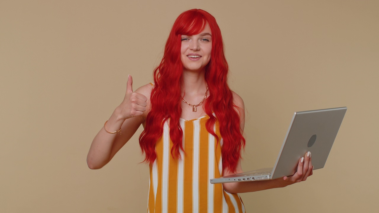 红发女孩在笔记本电脑上上网竖起大拇指积极的良好反馈，像是中了彩票视频素材