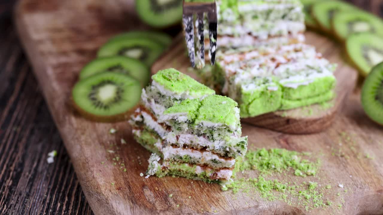 用叉子拿一块水果口味的绿色蛋糕和绿色猕猴桃切片视频素材