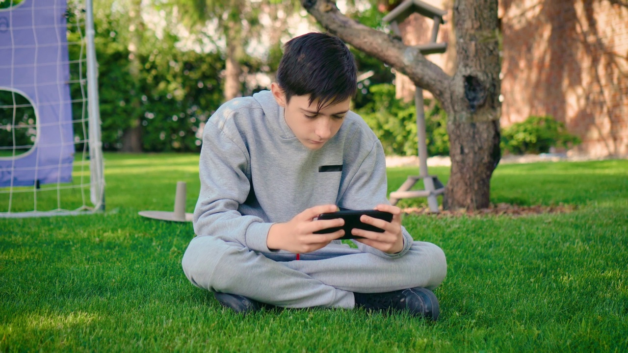 男孩在房子附近的花园里用手机上网视频素材
