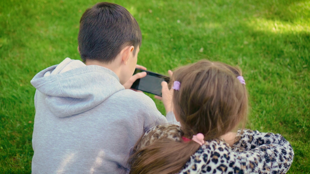 回望男孩和女孩对手机游戏的依赖。孩子们不能扔平板电脑和在户外玩耍视频素材