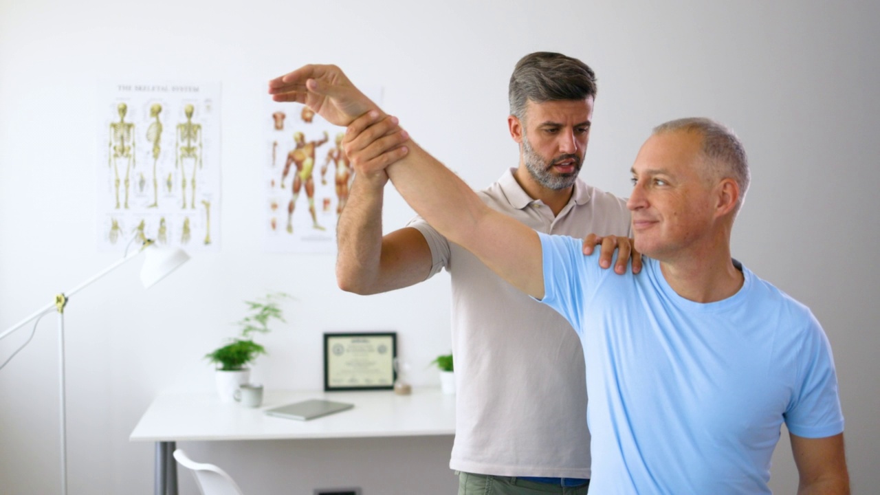男性理疗师在临床中帮助成熟男性锻炼肘部。视频素材