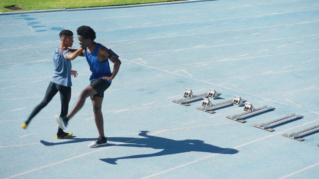 年轻的男性短跑运动员在阳光明媚的跑道上做起跑伸展运动视频素材