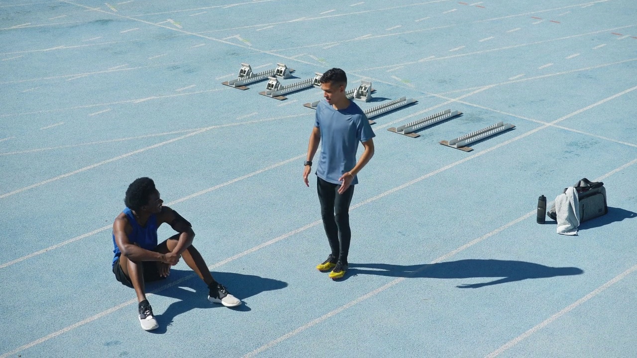 年轻的男性田径运动员在阳光明媚的跑道上伸展身体视频素材