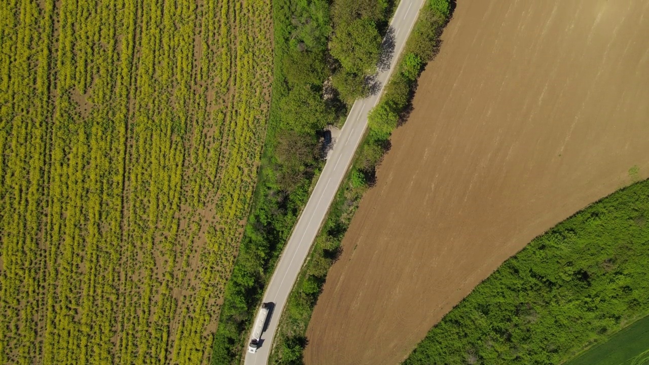 4K视频无人机拍摄的农田之间的道路上行驶的汽车视频下载