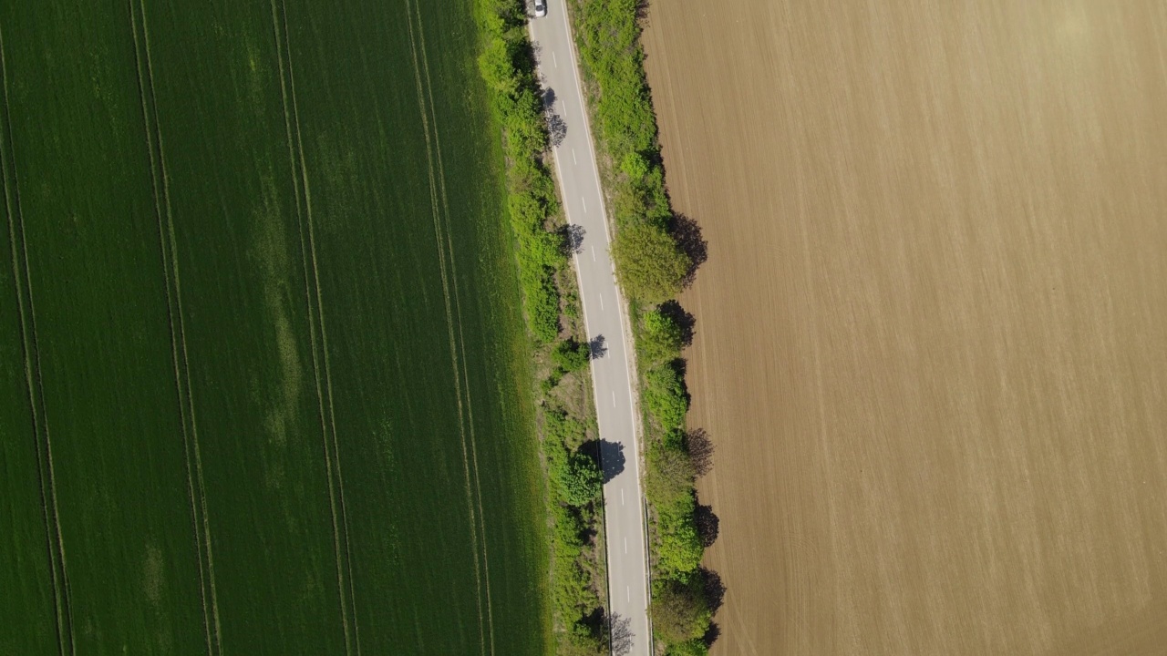 4K视频无人机拍摄的农田之间的道路上行驶的汽车视频下载