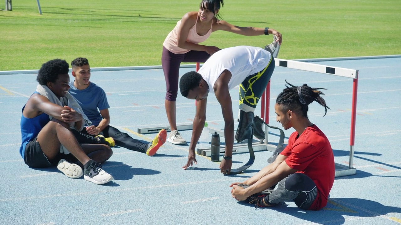 年轻的田径运动员在阳光明媚的跑道上伸展身体视频素材
