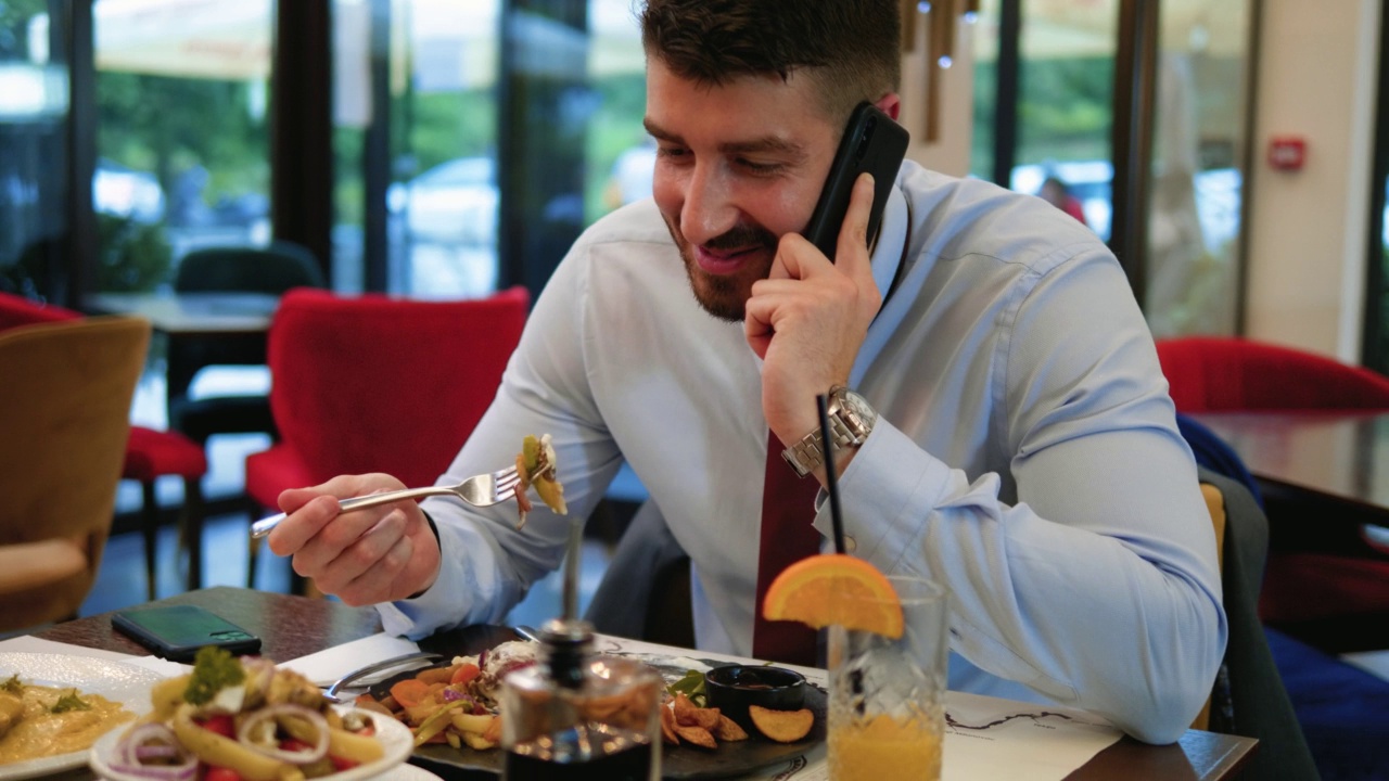手持拍摄的一个商人在餐厅吃午饭时打电话视频下载
