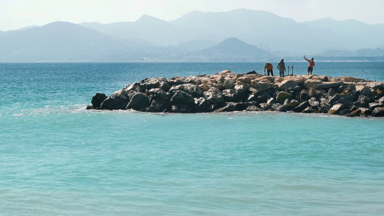 法国戛纳地中海沿岸。沙滩上的岩石和休息的人们视频素材