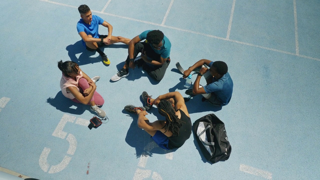 田径运动员在阳光明媚的蓝色跑道上交谈视频素材