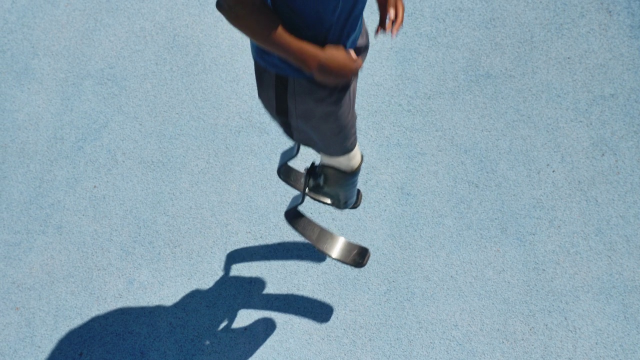 年轻的男性截肢运动员在阳光明媚的蓝色跑道上跑步视频素材