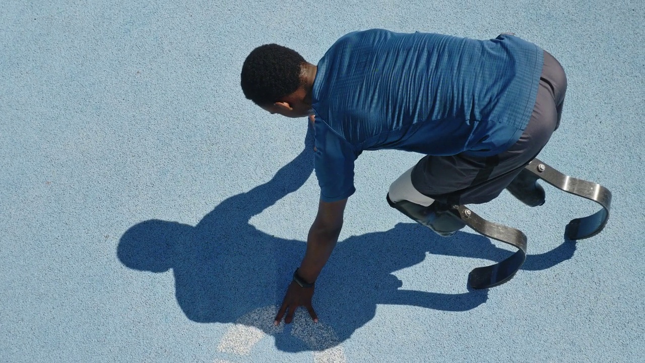年轻的男性截肢短跑运动员在阳光明媚的蓝色跑道上跑步视频素材