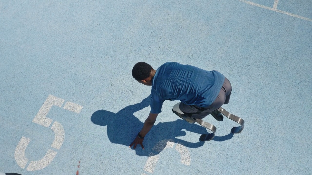 年轻的男性截肢运动员在阳光明媚的蓝色跑道上跑步视频素材