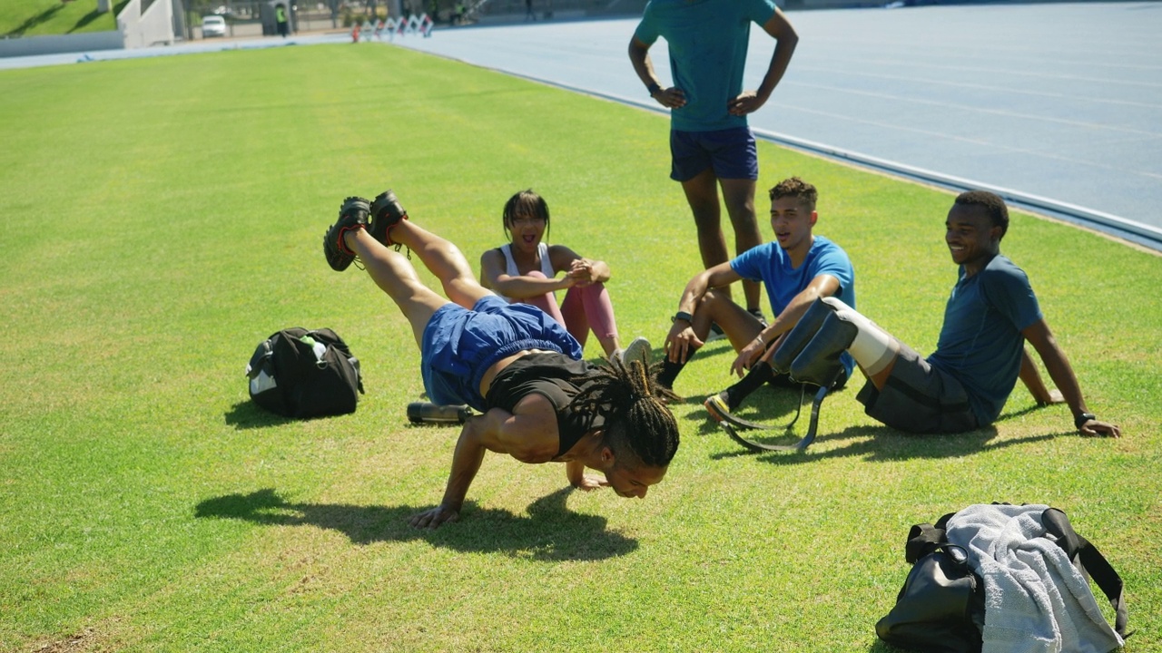 田径运动员看着朋友在草地上做倒立视频素材