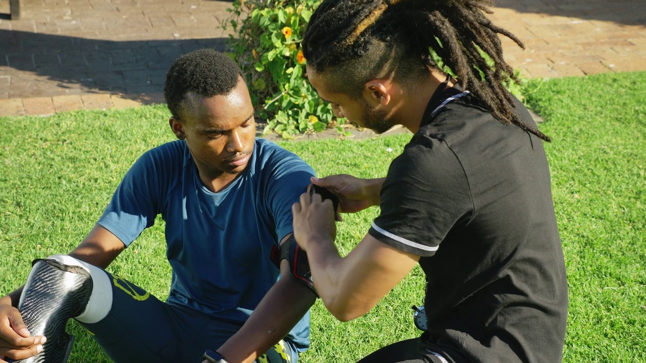 男教练在公园里帮助带臂章的截肢运动员视频素材