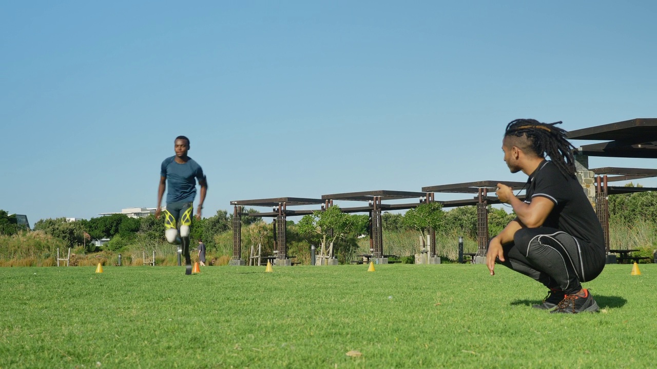 男教练定时截肢运动员在阳光公园短跑视频素材
