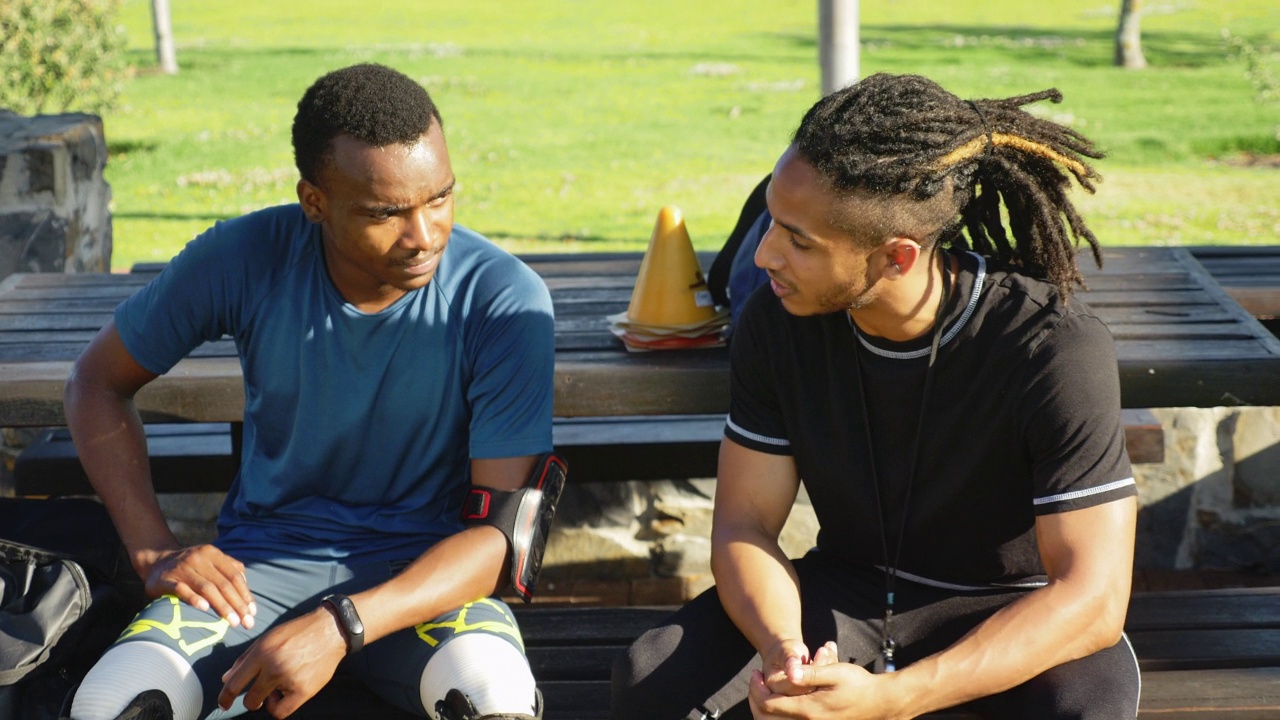 男教练和截肢运动员在阳光公园聊天视频素材