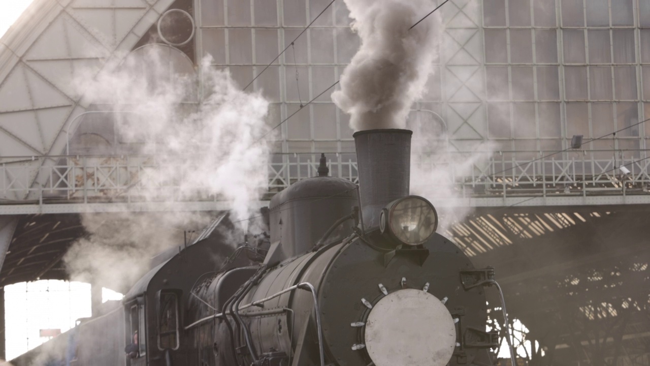 复古的蒸汽火车从火车站出发。老式黑色蒸汽火车，车厢是蓝色的视频下载