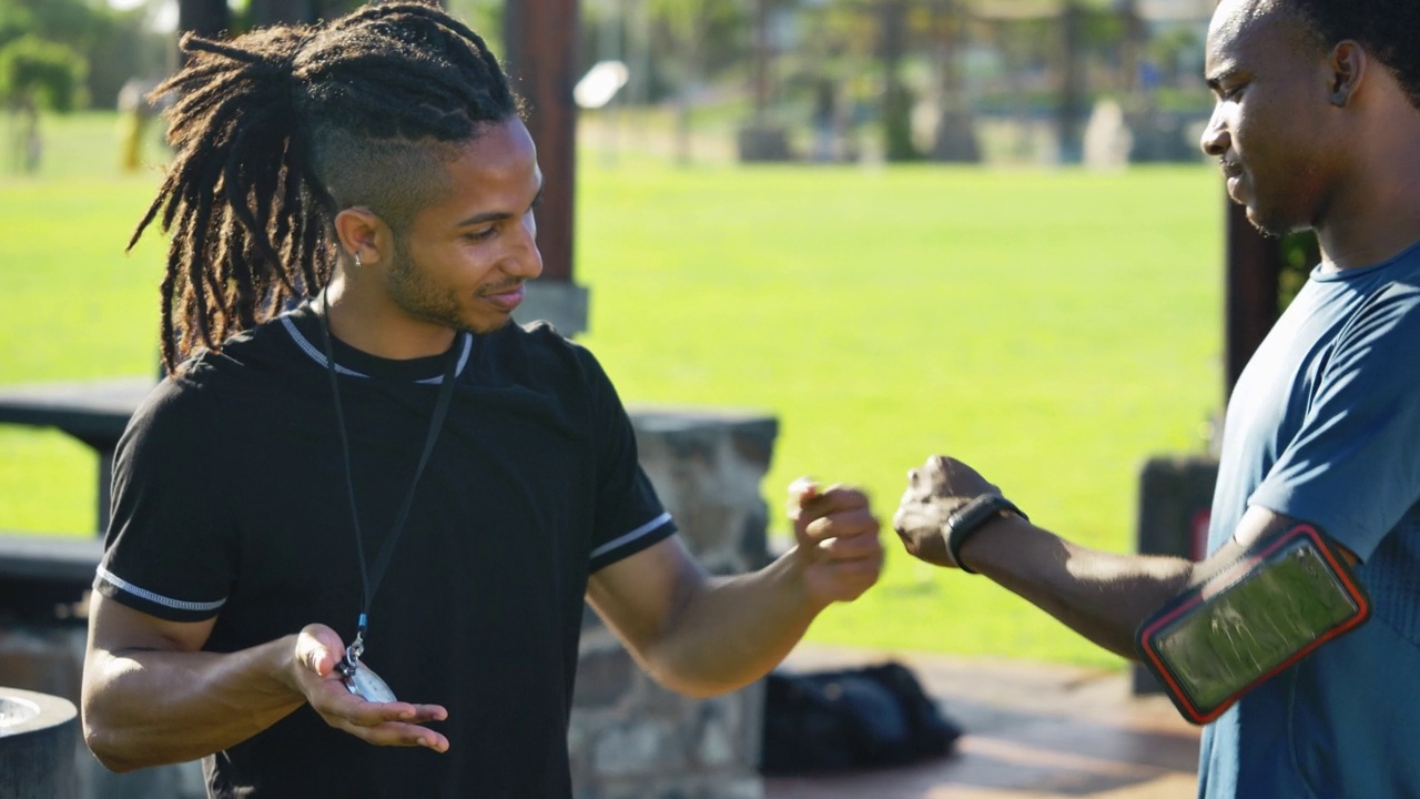 男教练和运动员在阳光明媚的公园里碰拳视频素材