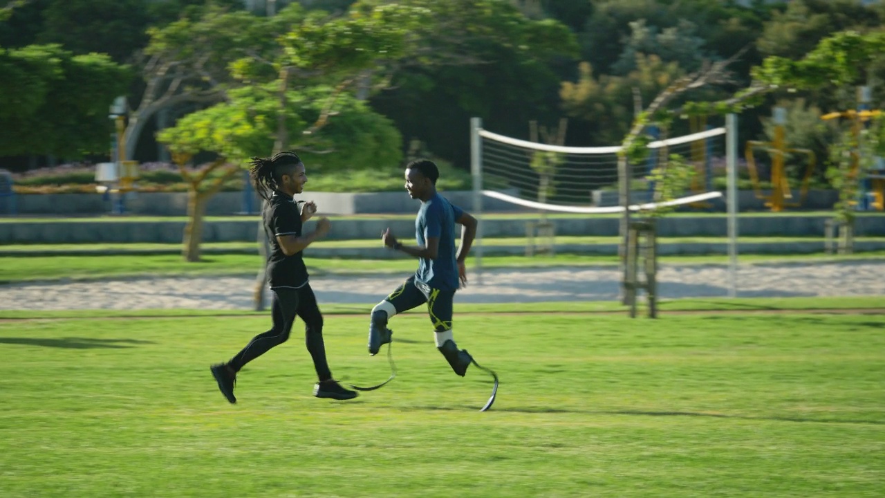 男性教练兼截肢短跑运动员在阳光公园慢跑视频素材