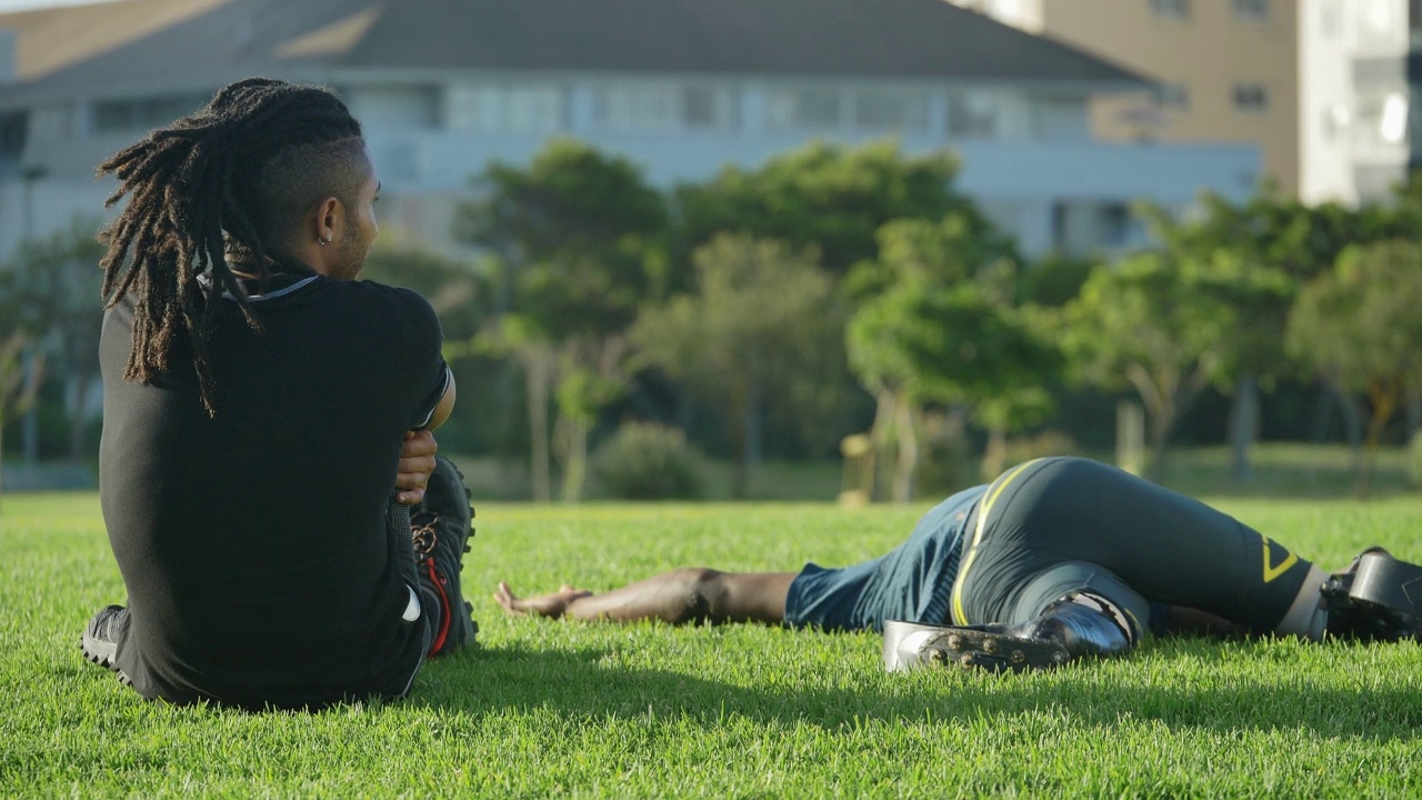 年轻的男教练兼截肢运动员在阳光明媚的草地上伸展视频素材