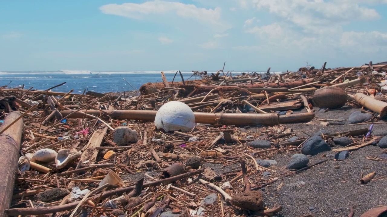 塑料瓶、塑料袋和其他垃圾被倾倒在海洋海滩的深色沙子上。视频素材