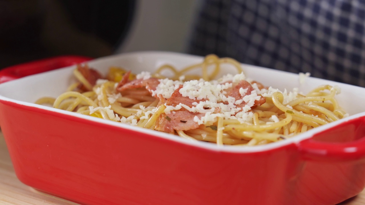 4k视频，在切达奶酪拍摄的视频片段正在被分级在刚煮好的意大利面盘子上。厨师磨马苏里拉奶酪。培根配甜椒意大利面。视频素材