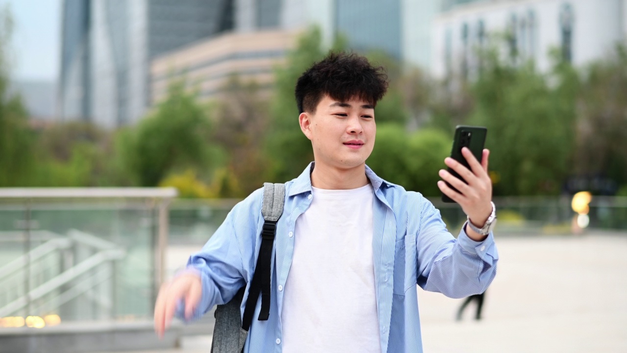 RT/亚洲年轻帅哥在城市街道上使用智能手机视频购买