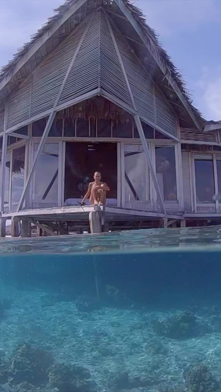 女子潜水和游泳在热带水上平房度假酒店。- - - - - -垂直格式视频下载
