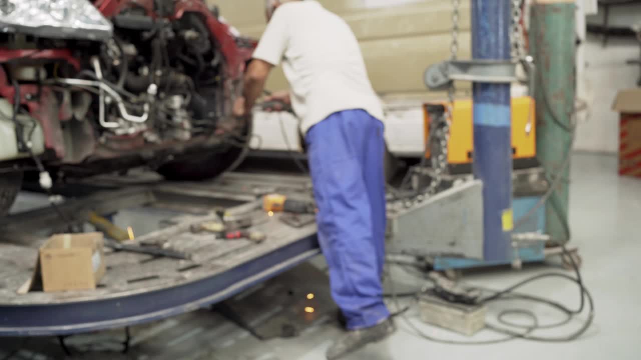 在一家汽车修理厂，工人正在焊接车架视频下载
