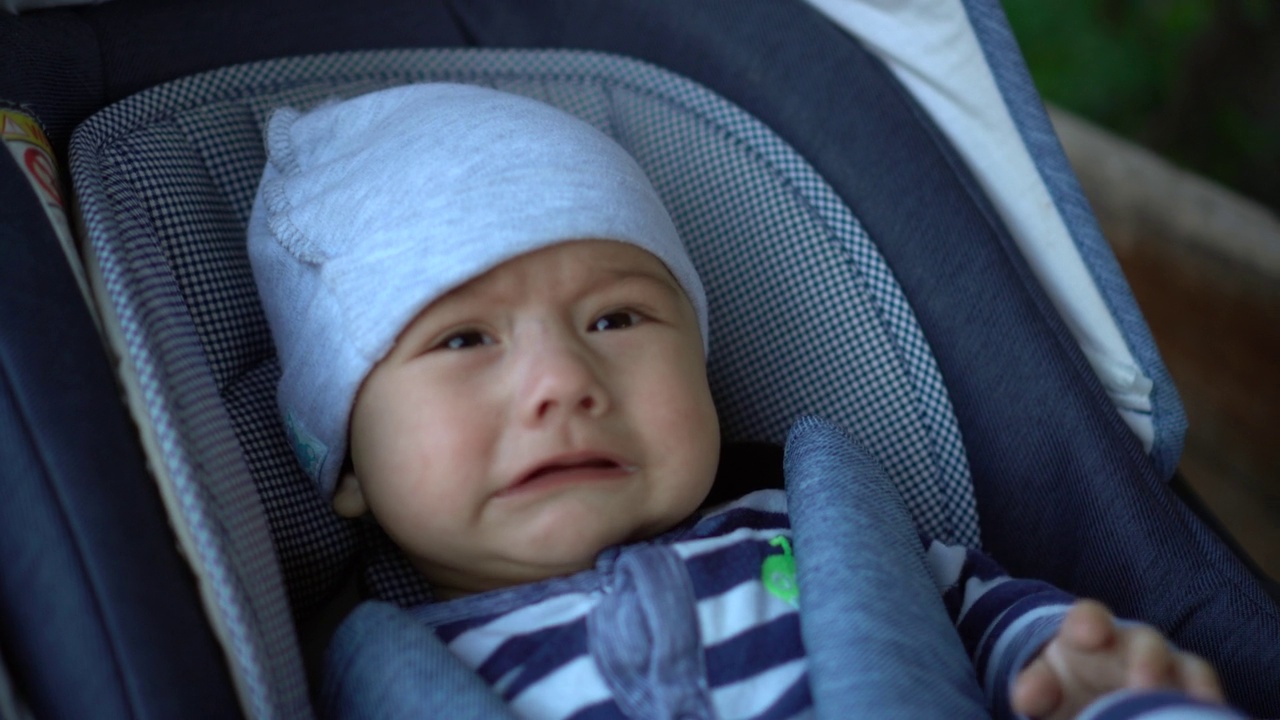 一个新生儿躺在婴儿车里哭泣。孩子身体不舒服。视频素材