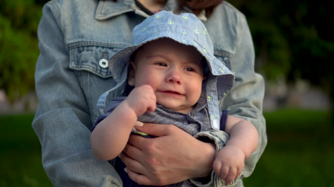 宝宝在妈妈的怀里走的特写。戴着巴拿马草帽的六个月大的婴儿微笑着。4 k视频素材