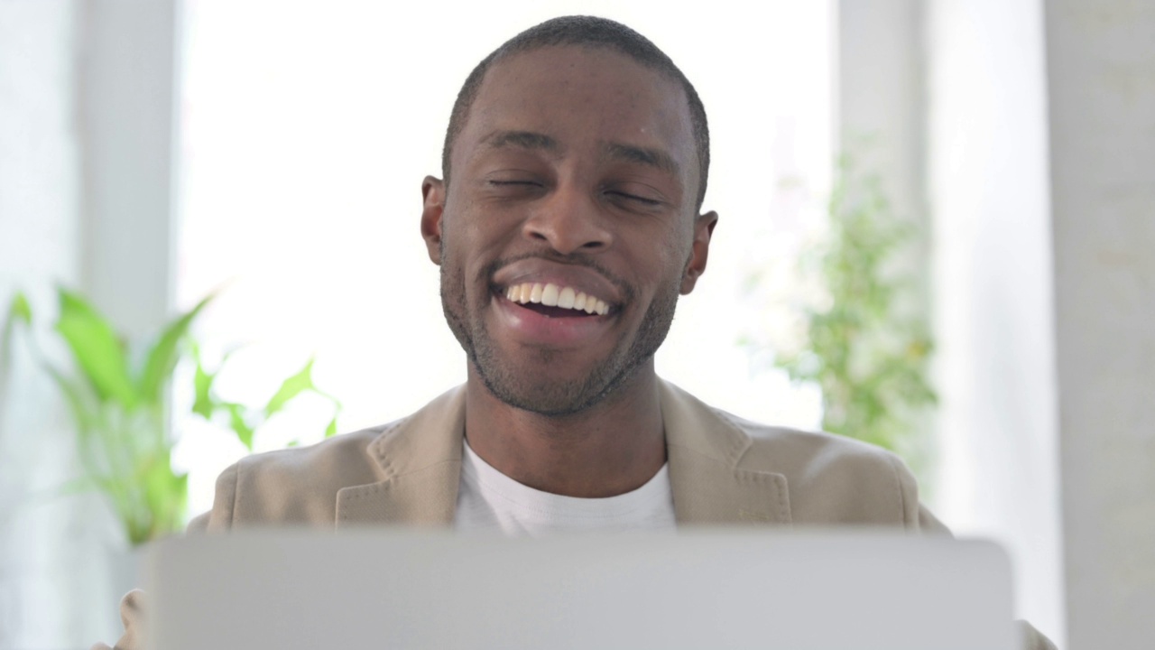 带着笔记本电脑的非洲男子在相机里微笑的特写视频素材