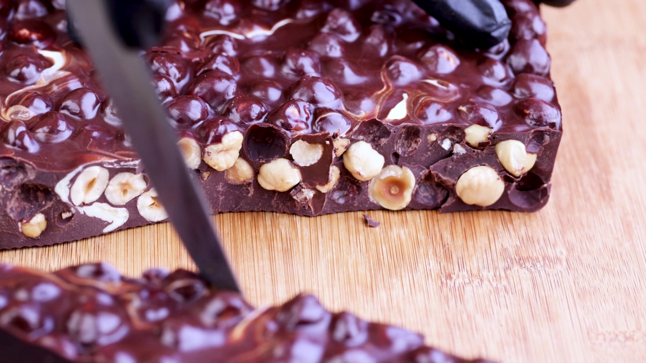 在木桌上把巧克力和榛子一起切成小块视频素材