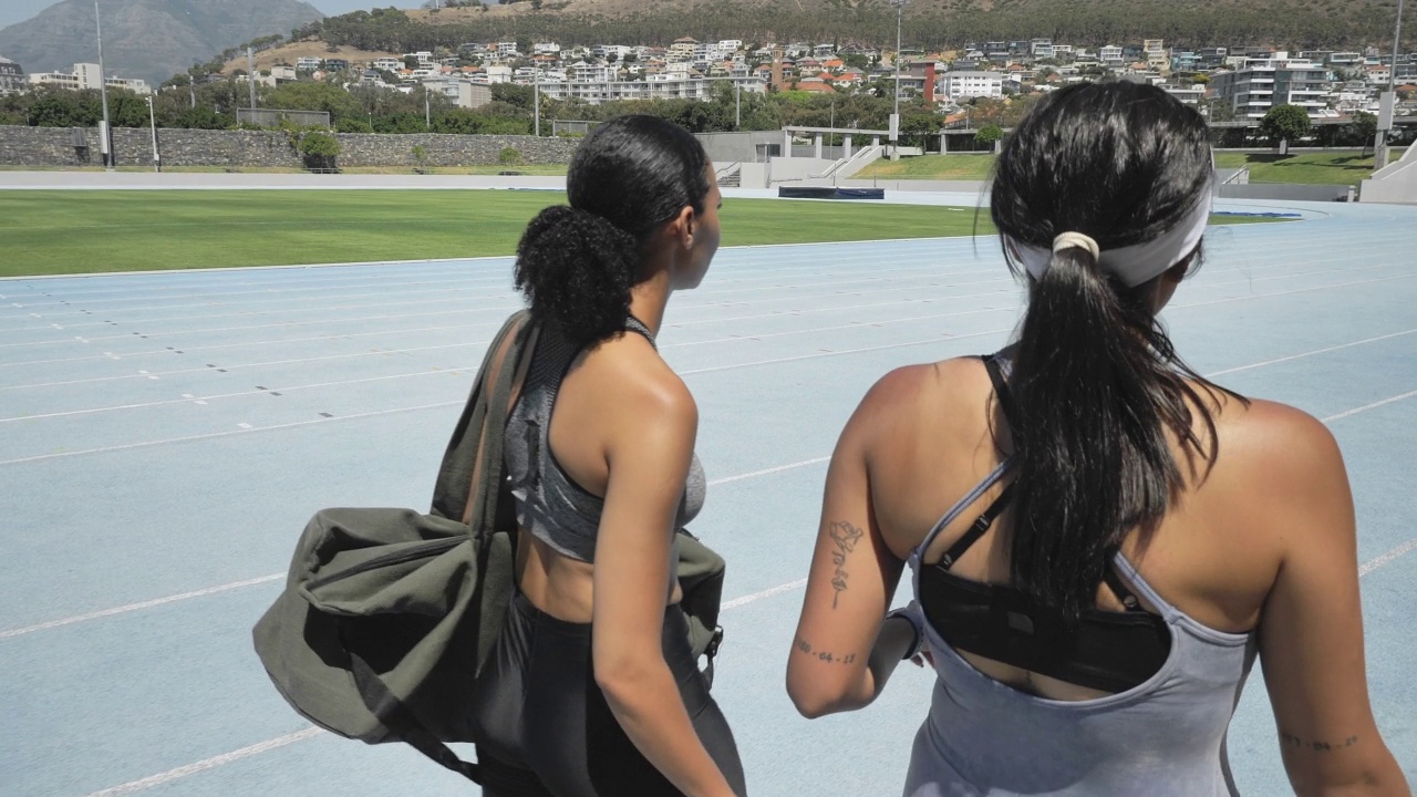 女田径运动员在阳光灿烂的运动场跑道上行走视频素材