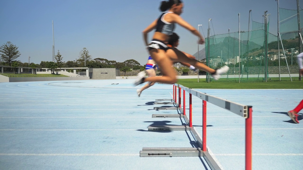 女性田径运动员在阳光明媚的跑道上跳栏视频下载