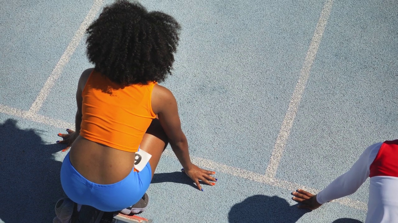 女子田径运动员在阳光跑道上准备起跑视频素材