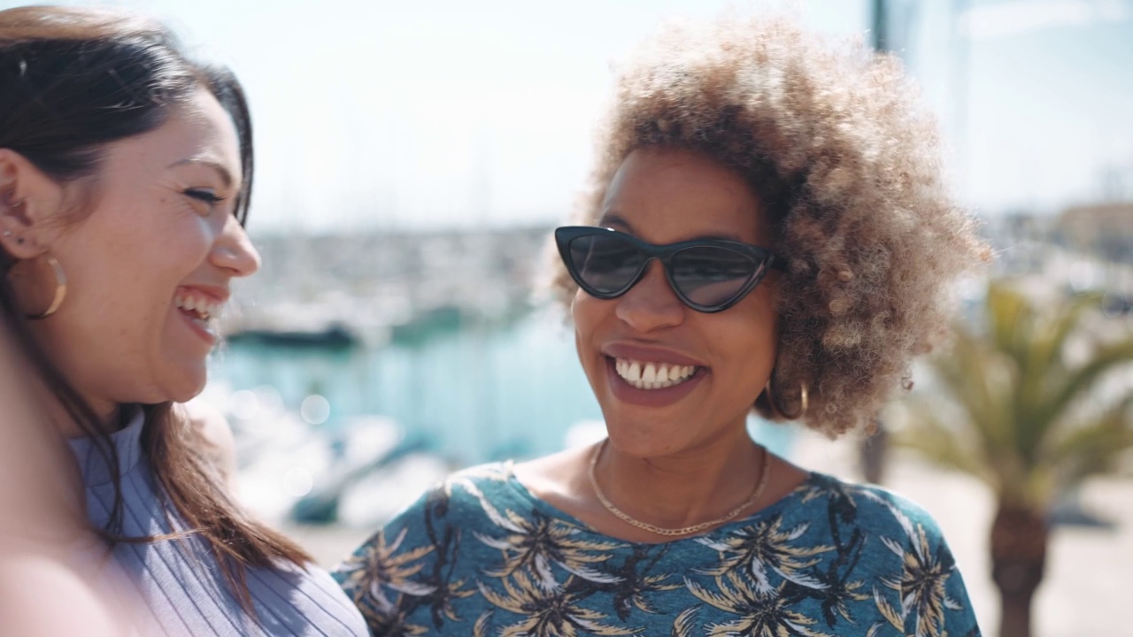 两名英俊的多民族女性在游艇附近的河堤上拍摄视频视频素材